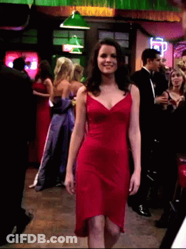 A Woman In A Red Dress Walks Through A Crowd GIF