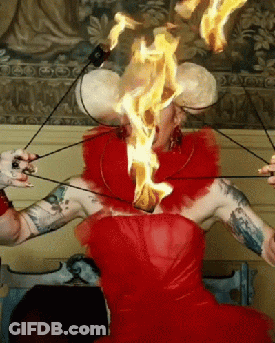 A Woman In A Red Dress With Flames Coming Out Of Her Head GIF
