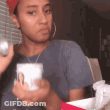 A Woman In A Red Hat Is Holding A Cup And A Ball In Her Hand . GIF