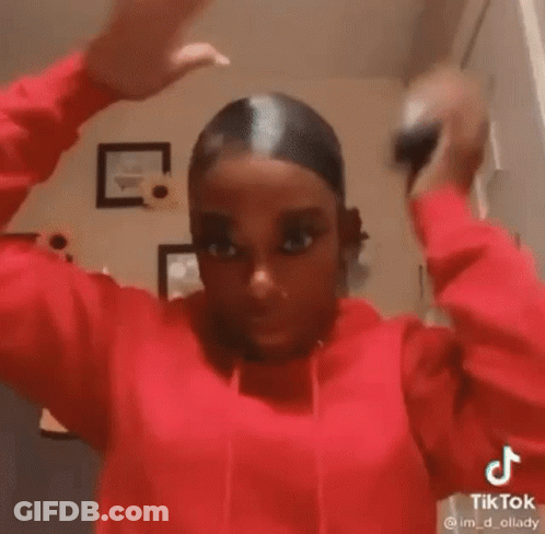A Woman In A Red Hoodie Is Holding Her Hair Up In A Bun . GIF