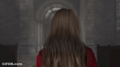 A Woman In A Red Jacket And Choker Looks At The Camera GIF