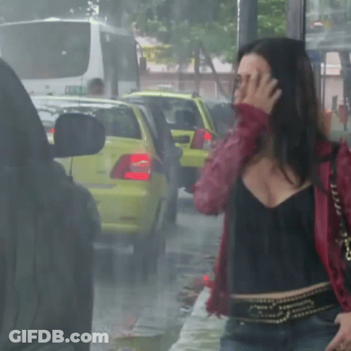 A Woman In A Red Jacket Covering Her Face In Front Of A Yellow Car GIF