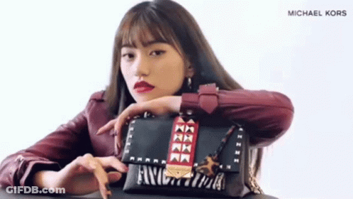 A Woman In A Red Jacket Is Holding A Michael Kors Bag . GIF