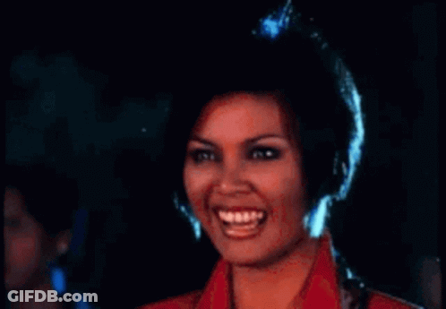 A Woman In A Red Jacket Is Laughing With Her Mouth Open . GIF