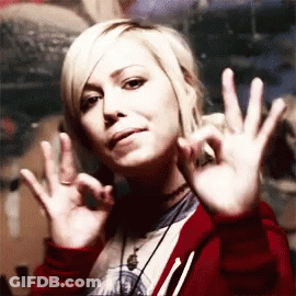 A Woman In A Red Jacket Is Making An Ok Sign With Her Hands GIF