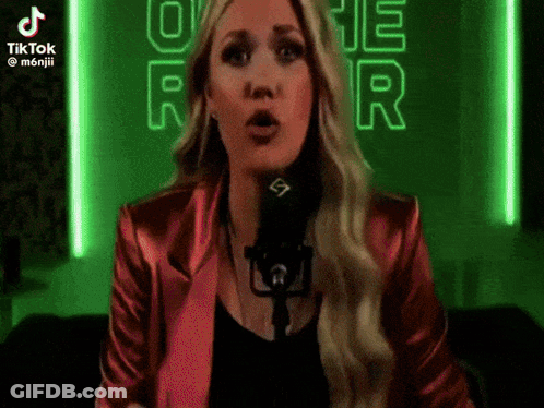 A Woman In A Red Jacket Is Singing Into A Microphone .. GIF