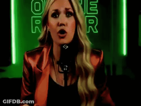 A Woman In A Red Jacket Is Singing Into A Microphone In Front Of A Neon Sign That Says Power . GIF