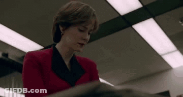 A Woman In A Red Jacket Is Sitting At A Table Reading A Book . GIF