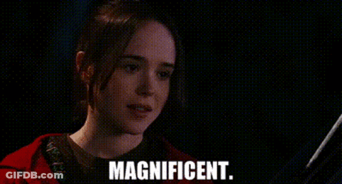A Woman In A Red Jacket Is Smiling In A Dark Room And The Words Magnificent Are On The Screen . GIF
