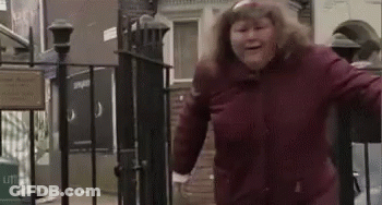 A Woman In A Red Jacket Is Standing In Front Of A Fence . GIF