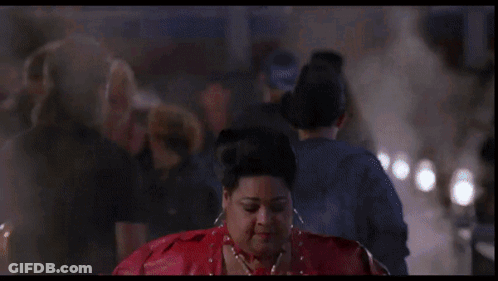A Woman In A Red Jacket Is Standing In Front Of A Neon Sign That Says ' A ' On It GIF