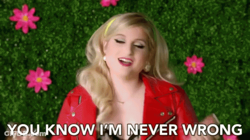 A Woman In A Red Jacket Is Standing In Front Of Pink Flowers . GIF
