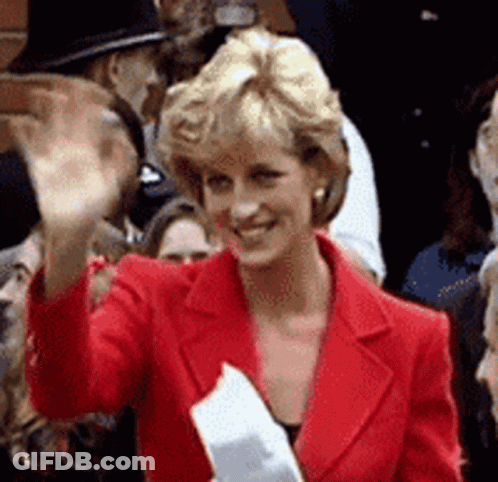 A Woman In A Red Jacket Is Waving At A Crowd GIF