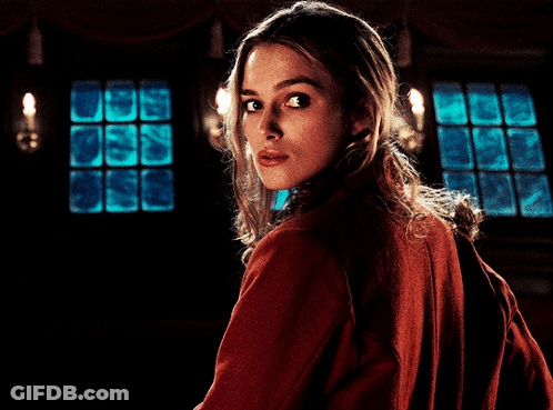 A Woman In A Red Jacket Looks Over Her Shoulder At The Camera GIF