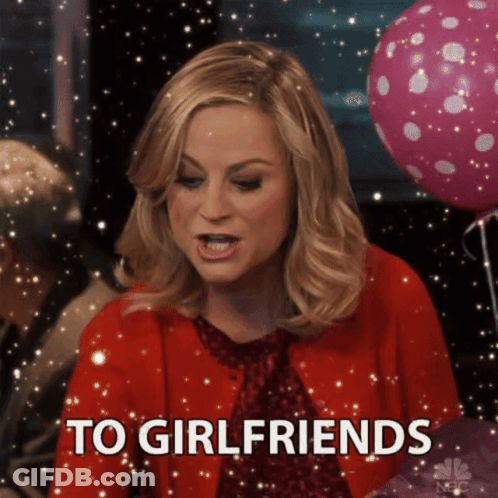 A Woman In A Red Jacket Says To Girlfriends In Front Of Pink Balloons GIF