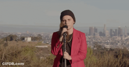 A Woman In A Red Jacket Sings Into A Microphone GIF