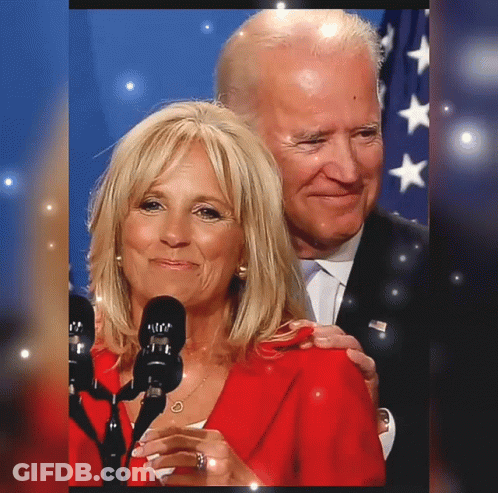 Woman In Red Jacket Next To Man In Black Suit GIF