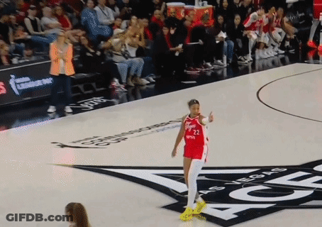 A Woman In A Red Jersey With The Number 22 On It Stands On A Basketball Court GIF