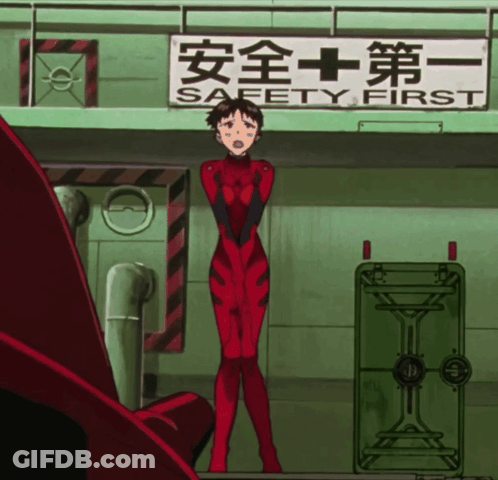 A Woman In A Red Jumpsuit Stands In Front Of A Sign That Says Safety First GIF