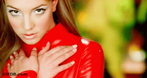 A Woman In A Red Latex Outfit Is Holding Her Hands On Her Chest . GIF