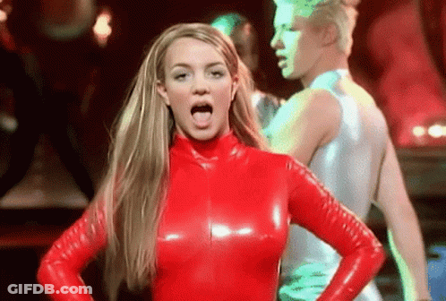 A Woman In A Red Latex Outfit Is Sticking Her Tongue Out While Standing In Front Of A Man . GIF