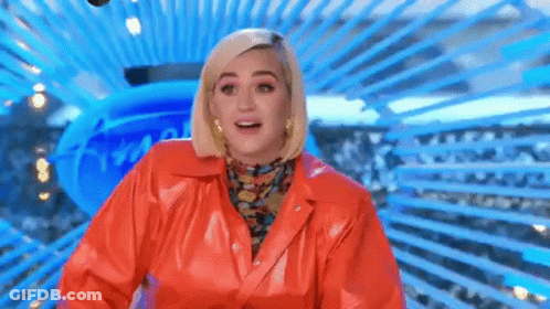 A Woman In A Red Leather Jacket Is Standing In Front Of A Blue Background And Smiling . GIF