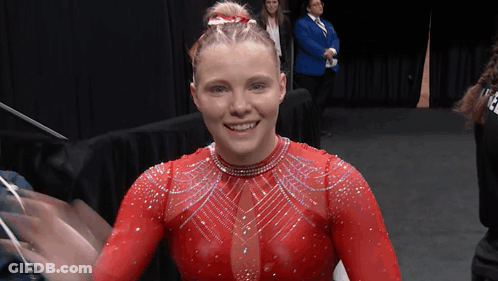 A Woman In A Red Leotard Is Smiling GIF