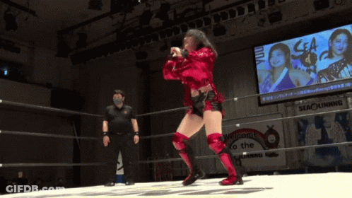 A Woman In A Red Outfit Is Dancing In A Wrestling Ring GIF