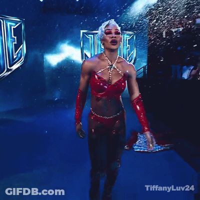 A Woman In A Red Outfit Stands In Front Of A Sign That Says Wheel Down GIF