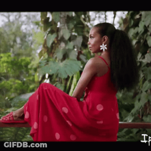 A Woman In A Red Polka Dot Dress Is Sitting On A Railing GIF