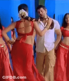 A Woman In A Red Saree Is Dancing With A Man GIF