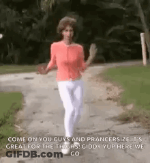 A Woman In A Red Shirt And White Pants Is Walking Down A Path . GIF