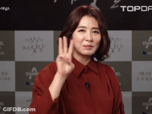 A Woman In A Red Shirt Giving A Peace Sign GIF