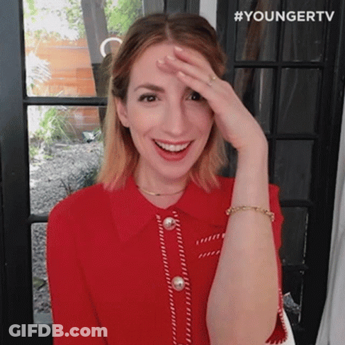 A Woman In A Red Shirt Is Covering Her Face With Her Hand And Smiling . GIF
