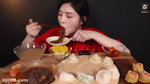A Woman In A Red Shirt Is Eating A Bowl Of Soup With Chopsticks GIF