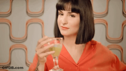 A Woman In A Red Shirt Is Holding A Glass GIF
