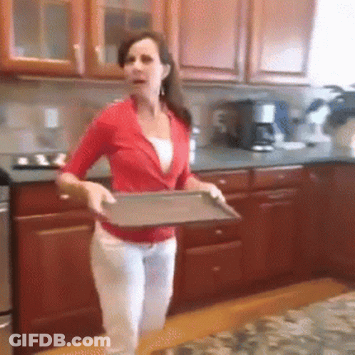 A Woman In A Red Shirt Is Holding A Metal Tray In A Kitchen GIF