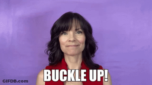 A Woman In A Red Shirt Is Holding A Red Stick And Says Buckle Up ! GIF