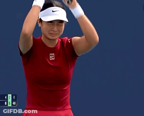 A Woman In A Red Shirt Is Holding A Tennis Racquet In Her Hand GIF