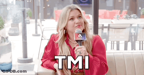 A Woman In A Red Shirt Is Sitting At A Table Holding A Microphone And Says Tmi . GIF