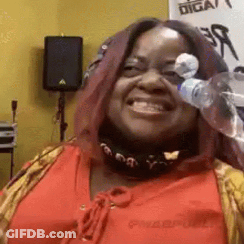 A Woman In A Red Shirt Is Smiling And Holding A Bottle Of Water In Front Of Her Face . GIF