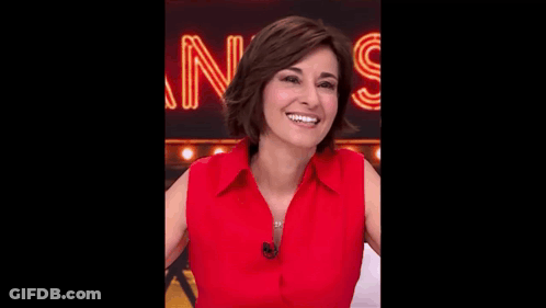 A Woman In A Red Shirt Is Smiling And Looking At The Camera . GIF