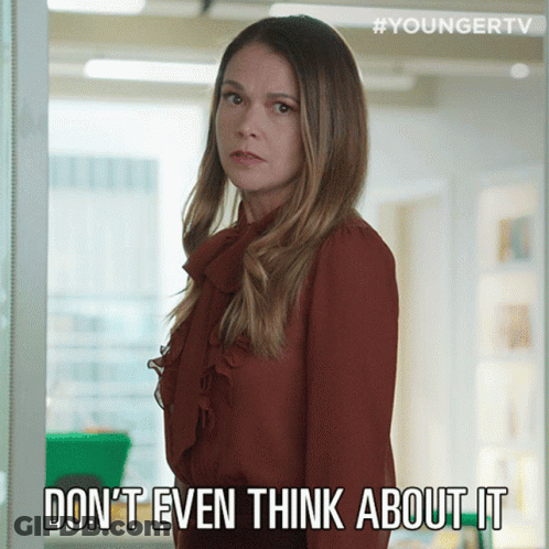 A Woman In A Red Shirt Is Standing In Front Of A Sign That Says " Do N't Even Think About It " GIF