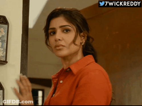 A Woman In A Red Shirt Is Standing In Front Of A Wall With A 7Wickreddy Logo Above Her GIF