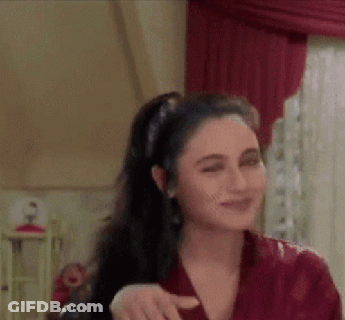 A Woman In A Red Shirt Is Standing In Front Of A Window In A Room . GIF