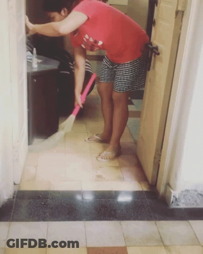 A Woman In A Red Shirt Is Sweeping The Floor With A Broom GIF