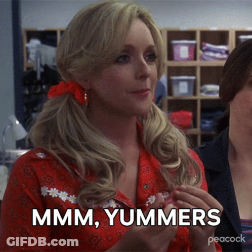 A Woman In A Red Shirt Says " Mmmm Yummers " While Holding Something In Her Hand GIF