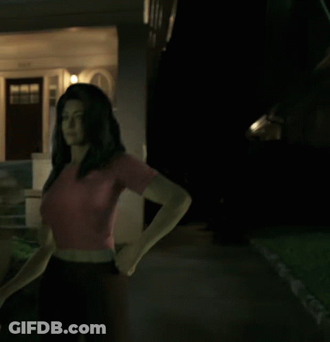 A Woman In A Red Shirt Stands In Front Of A House GIF