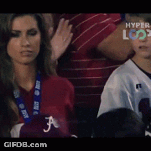 A Woman In A Red Shirt With The Letter F On It Looks At A Boy In A White Jersey GIF