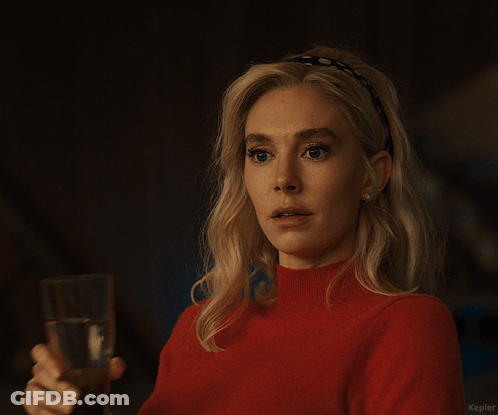A Woman In A Red Sweater Holds A Glass Of Water In Her Right Hand GIF